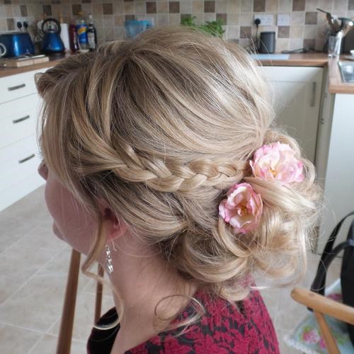Low curly updo with braid and flowers